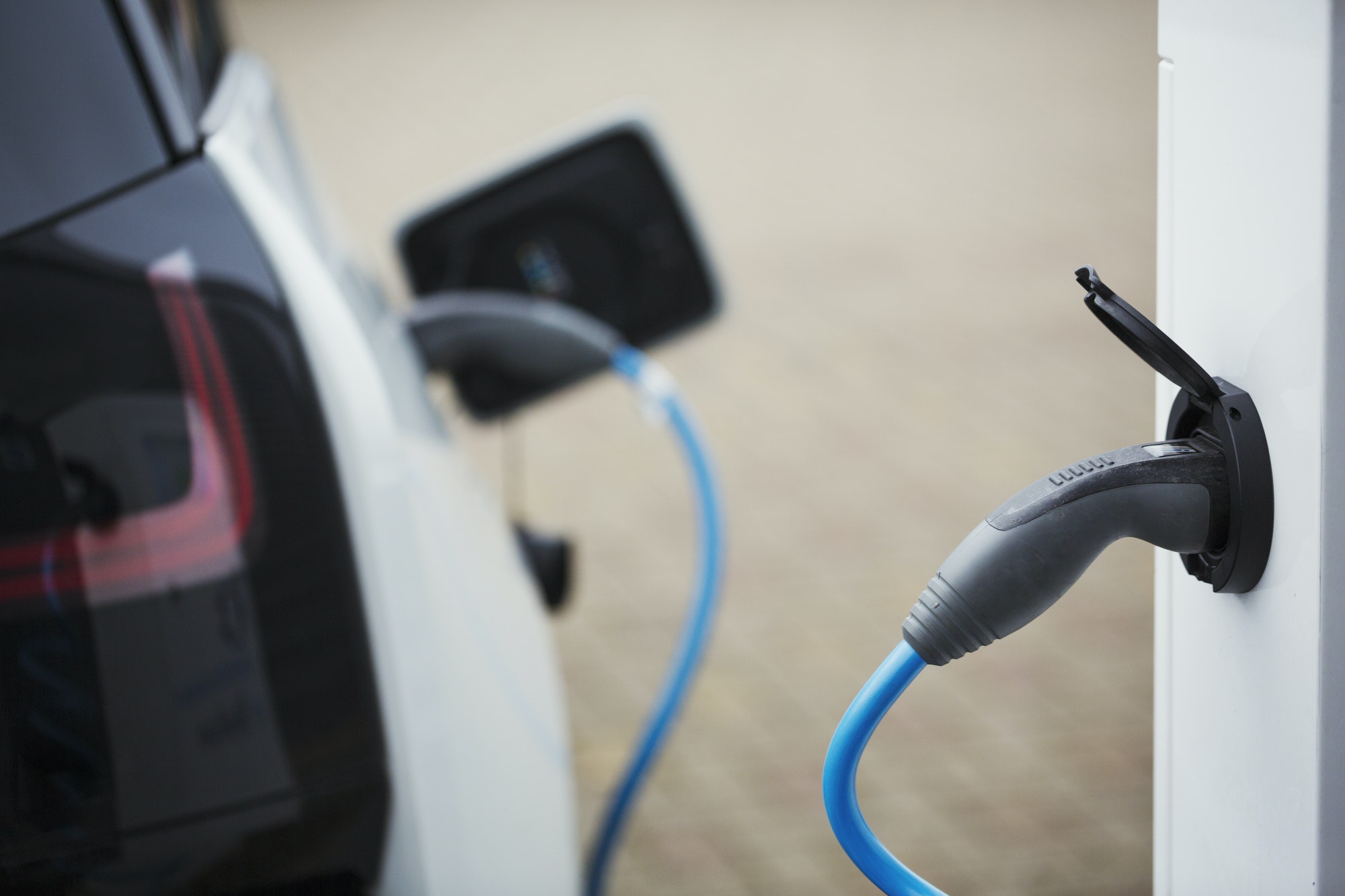 Electric car being charged with a cable connected to a wall socket.